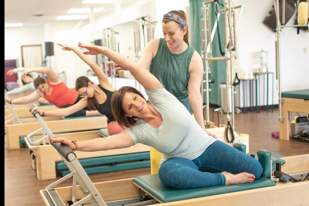 A group of clients using a Pilates Reformer with the instruction of the teacher